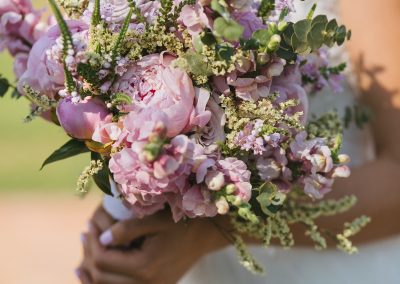 Beautiful elegant summer wedding bouquet of pink peonies, roses and wildflowers in the hands of the bride.